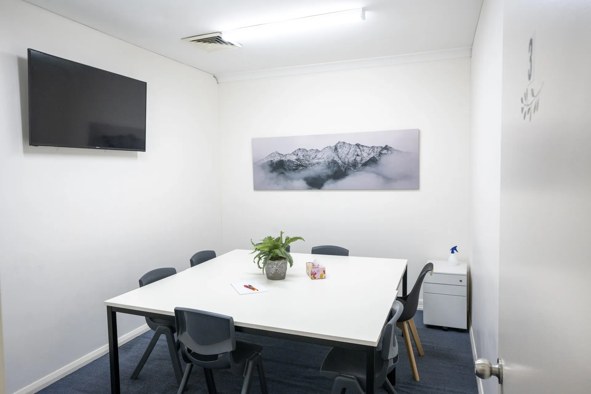 A classroom with a wall-mounted screen