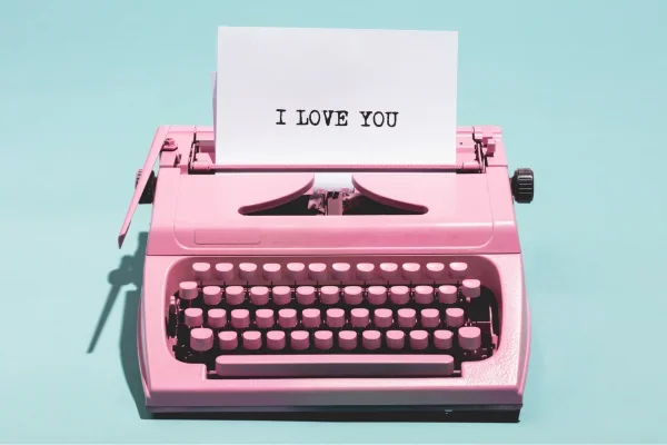 A pink typewriter with a sheet of paper that simply says I LOVE YOU
